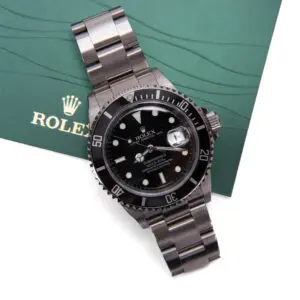 Luxury black Rolex watch on green background.