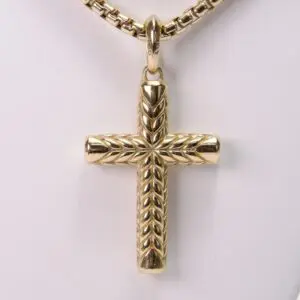Gold cross pendant with intricate design.