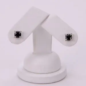 Black stud earrings on white display stand.