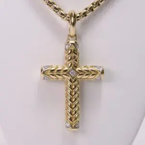 Gold cross pendant with intricate braided design.