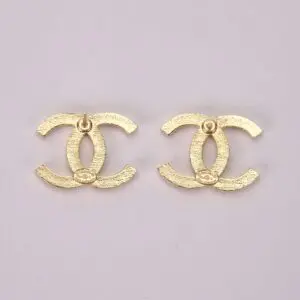 Gold Chanel logo earrings on display.