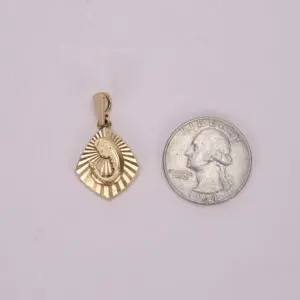 Gold pendant beside a quarter coin.