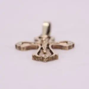 Gold cross pendant on soft background.