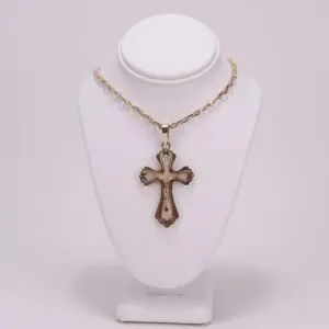 Gold cross necklace on display stand.