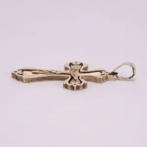 Gold cross pendant on light background.