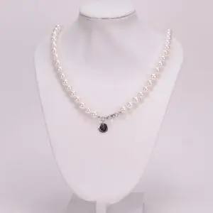 Pearl necklace displayed on white mannequin bust.