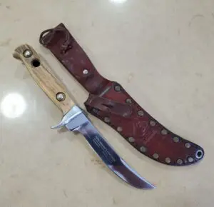 Knife with wooden handle and leather sheath.