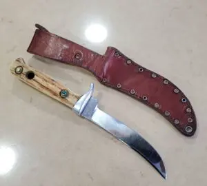 Knife with leather sheath on table.