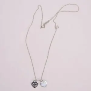 Silver heart pendant necklace with two charms.