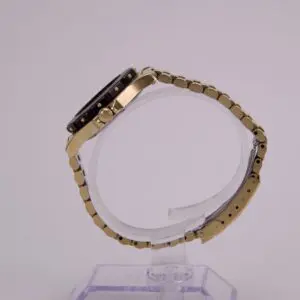 Gold wristwatch on transparent display stand.
