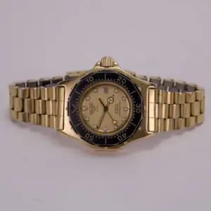 Gold wristwatch with black bezel, white dial.