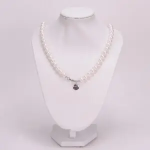 Pearl necklace on a white display stand.
