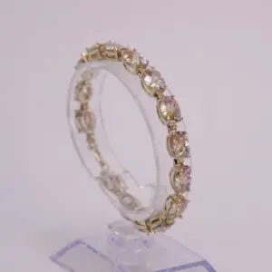 Gold bracelet with oval gemstones on stand.