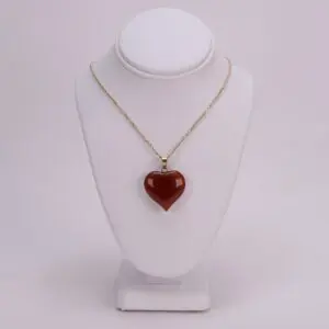 Gold necklace with red heart pendant.
