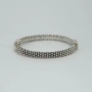 Silver bracelet with beaded design on display.