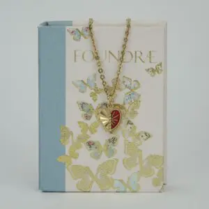 Heart pendant necklace on butterfly-patterned book.