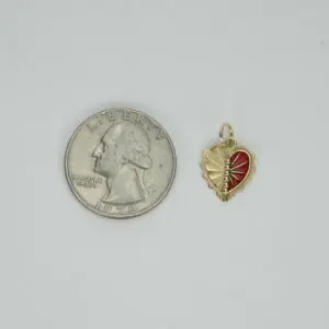 Red heart pendant beside a US quarter.