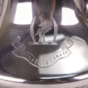 Engraved silver item with emblem and motto.