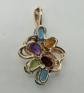 Gold pendant with colorful gemstones, intricate design.