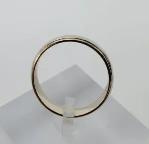 Gold ring displayed on clear stand.