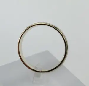 Gold wedding band displayed on stand.