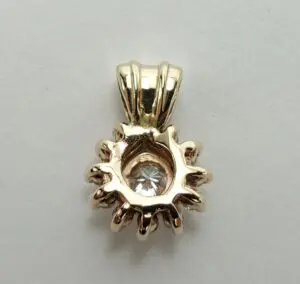 Gold pendant with a central clear gemstone.