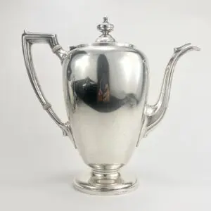 Silver teapot with ornate handle and spout.
