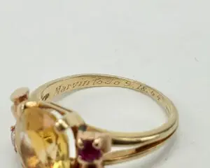 Gold ring with gemstones and engraved inscription.