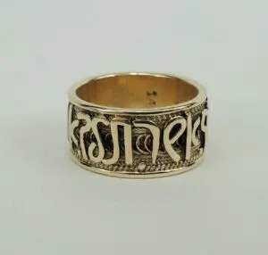 Gold ring with engraved decorative script.