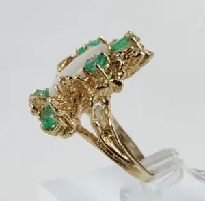 Gold ring with green gemstones and pearl.