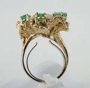 Gold ring with green gemstones, intricate design.