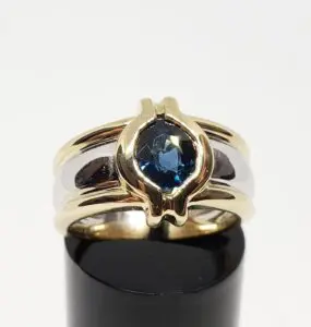 Gold ring with blue gemstone on display.