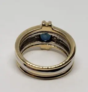 Gold ring with blue gemstone inside band.