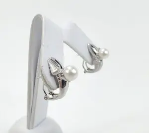 Silver earrings with pearls on display stand.