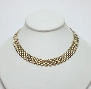 Gold chain necklace on a display stand.