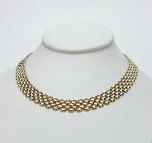 Gold choker necklace on white display stand.