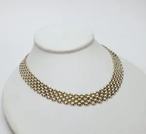 Gold chain necklace on display stand.