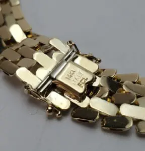 Gold bracelet clasp with engraved markings.