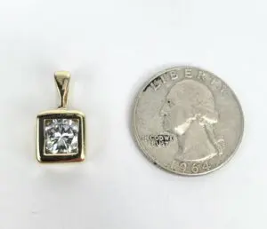 Gold pendant with diamond next to coin.