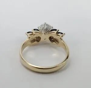Gold ring with diamond and dark gemstones.