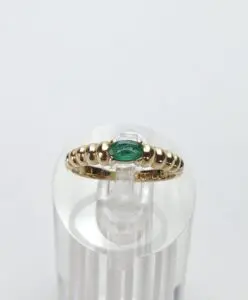 Gold ring with green stone on display.