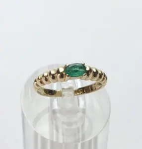 Gold ring with green gemstone on stand.