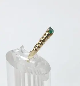 Gold ring with green gemstone on stand.
