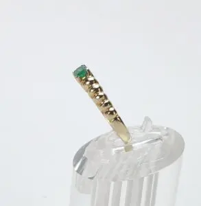 Gold ring with green gemstone on stand.