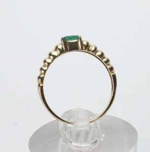 Gold ring with green gemstone on stand.