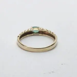 Gold ring with turquoise gemstone, white background.