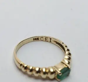 Gold ring with green gemstone and engraving.