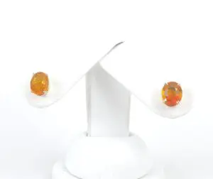 Orange gemstone stud earrings on display stand.
