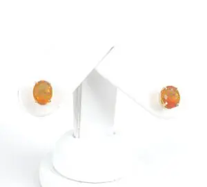 Orange gemstone earrings on white display stand.