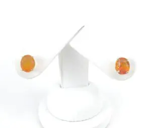 Orange gemstone earrings on white display stand.